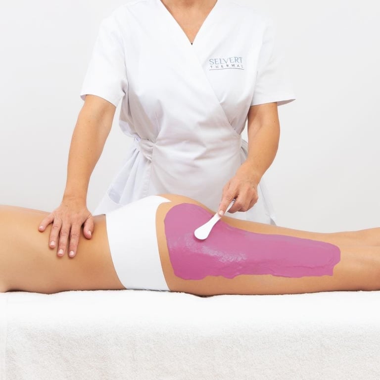 Esthetician applying pink wax to clients leg during hair removal treatment
