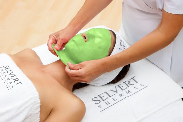 Spa therapist performing facial treatment with green mask applicator